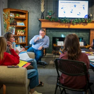 Trainer drinks from a mug while attendees discuss during the Wichita PCM® communication workshop in Wichita, Kansas.