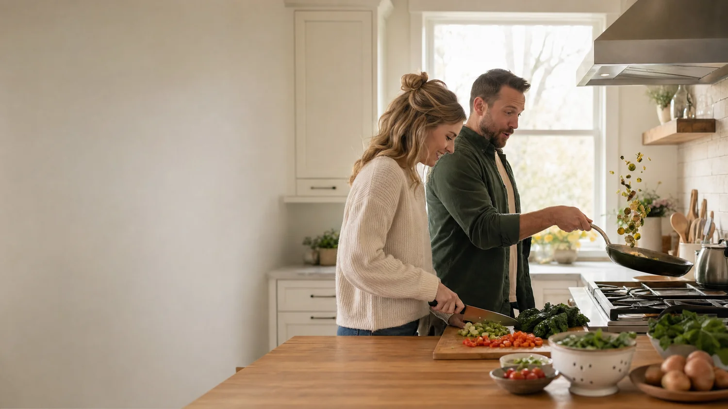 A white / Caucasian couple (one woman, one man) cooking side by side at a kitchen counter, one chopping vegetables in a slow neat pile while