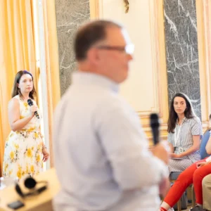 Sarah Thome answers with a microphone from the audience while a speaker listens in the foreground at the Bordeaux PCM® International Conference.