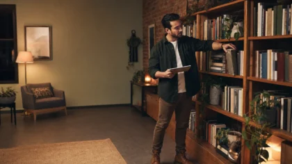 A Hispanic / Latino person, a therapist in a warm consulting office, sliding a well-worn reference book back onto a crowded shelf while glancing