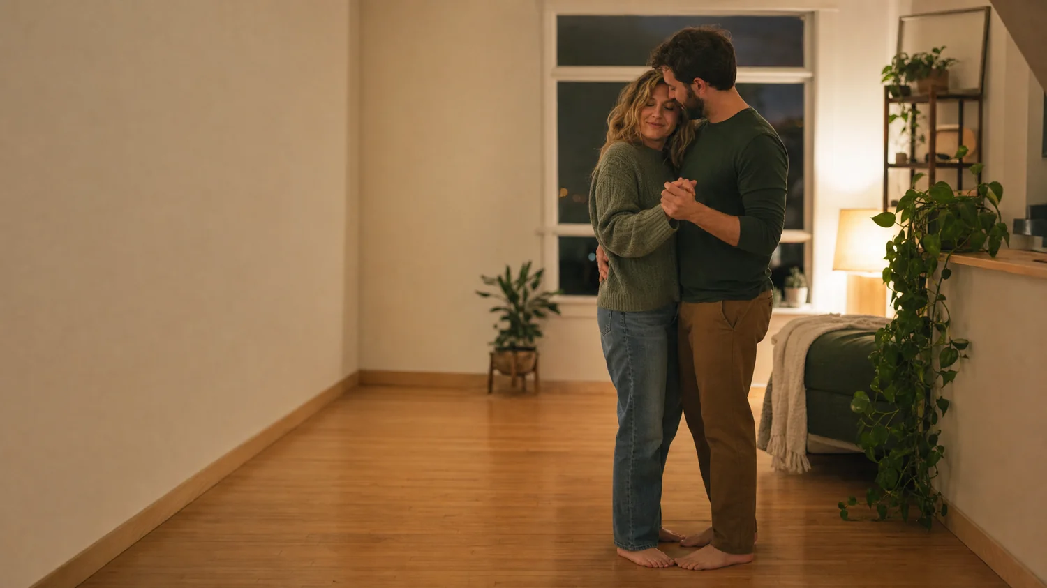 A white / Caucasian couple (one woman, one man) slow-dancing barefoot in a softly lit living room — Is It Okay to Plan Intimacy? 5 More Relationship Myths Therapists Want You to Rethink