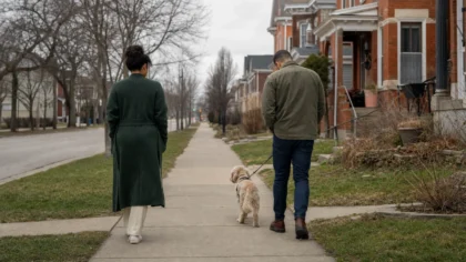 From behind, a multiracial couple (one woman, one man) walking a dog together along an overcast neighborhood sidewalk with a noticeable gap — Why Won